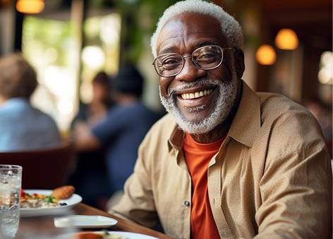 Happy elderly afro american man sitting at table